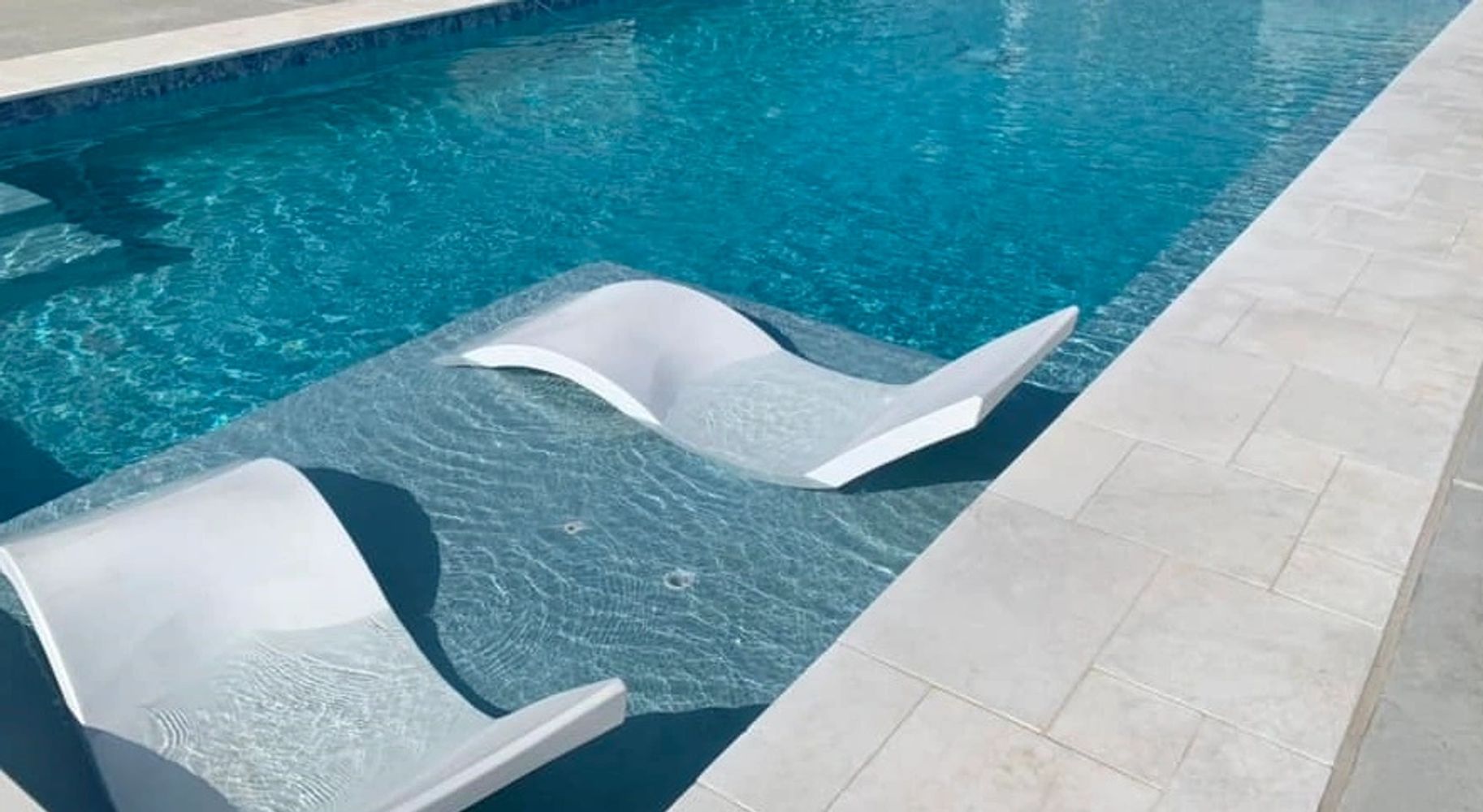 Modern custom pool with sun shelf and in-pool lounge chairs